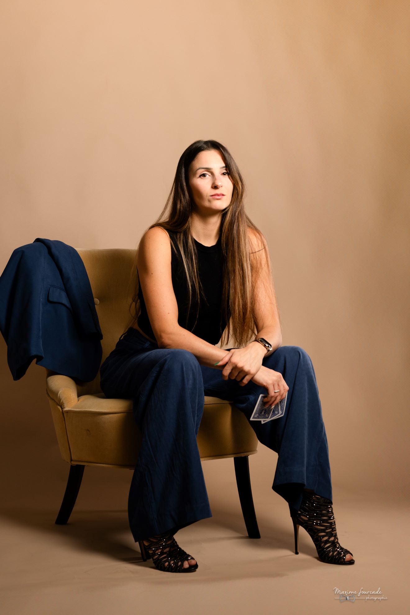 Manon Castello, magicienne de close-up, assise sur une chaise, cartes à la main